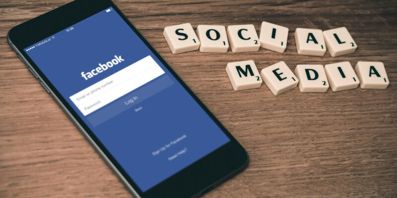 Phone open to facebook and scrabble tiles spelling social media